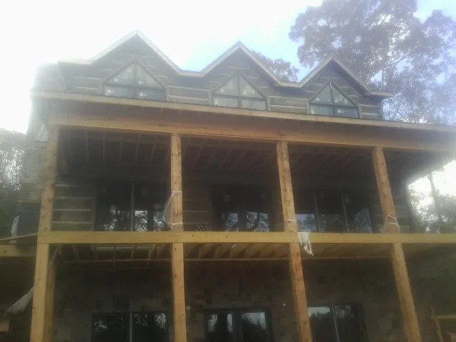 Dormers and porch framing on a large log home under construction — Roof Coating work by our crew in Central Village
