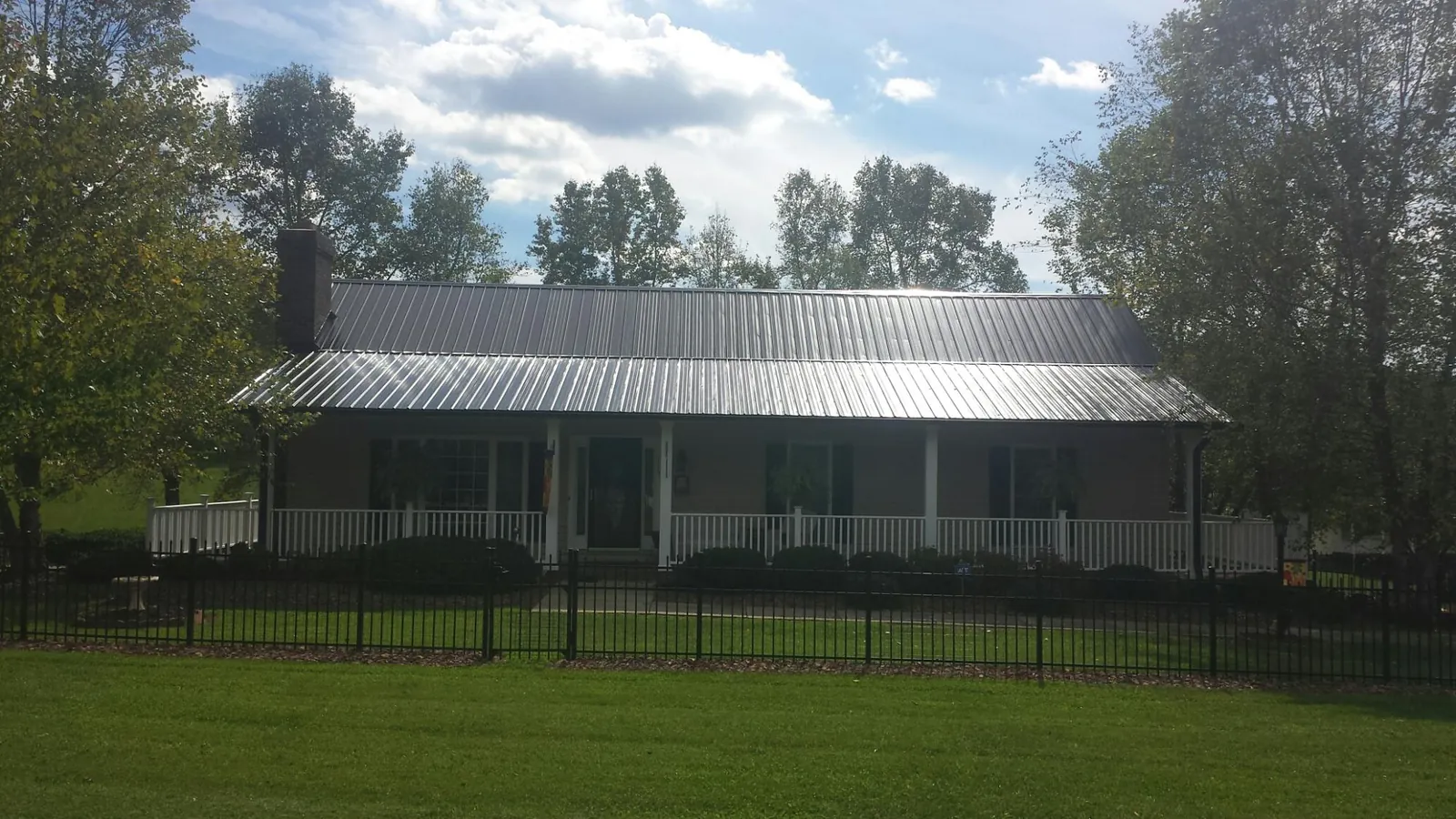 Gray metal roof on a brick ranch with a full width front porch — Gutter Guard Installation work by our crew in Central Village