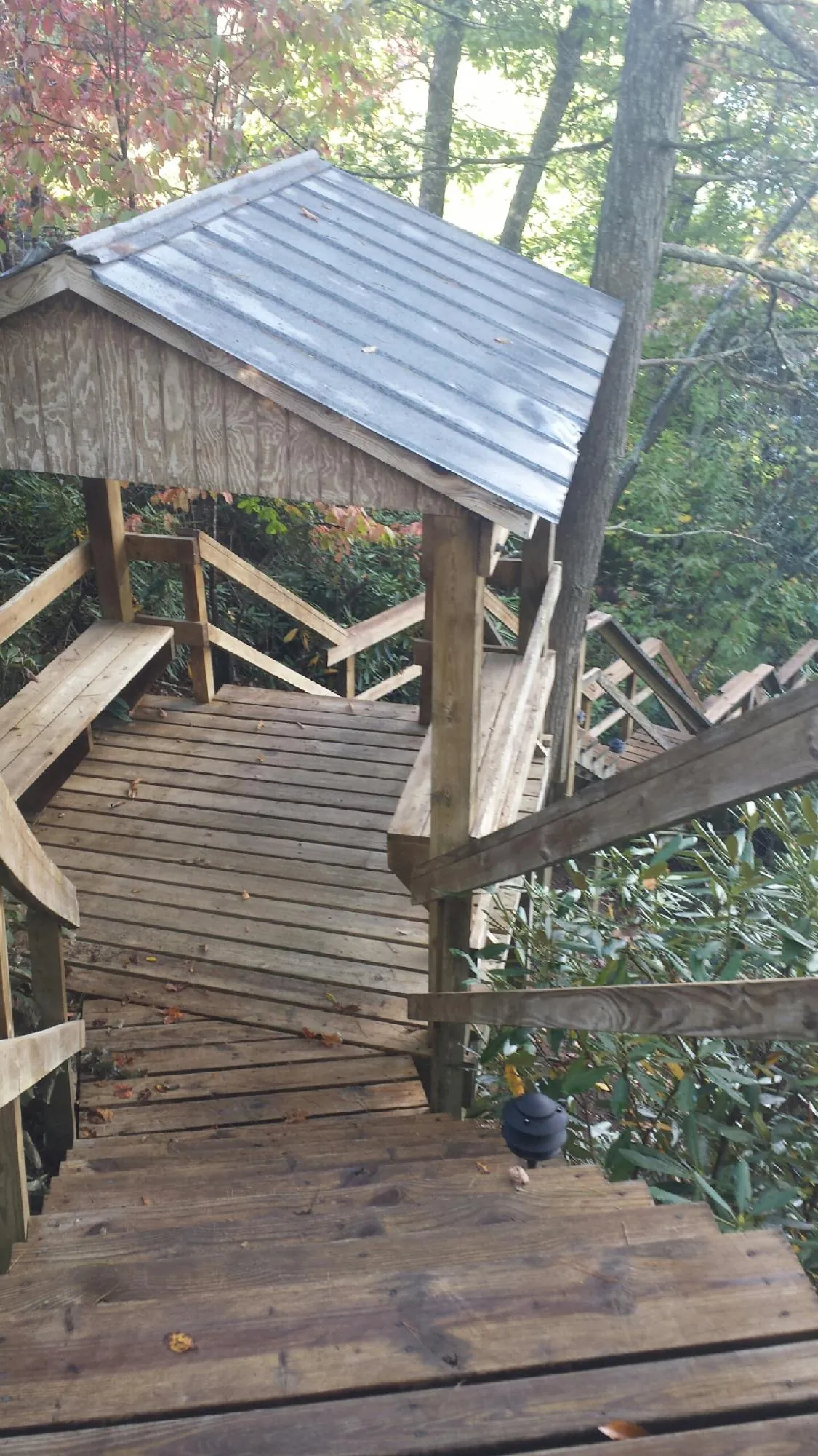 Metal roofed shelter over wooden steps on a wooded walkway — Skylight Repair & Installation work by our crew in Central Village