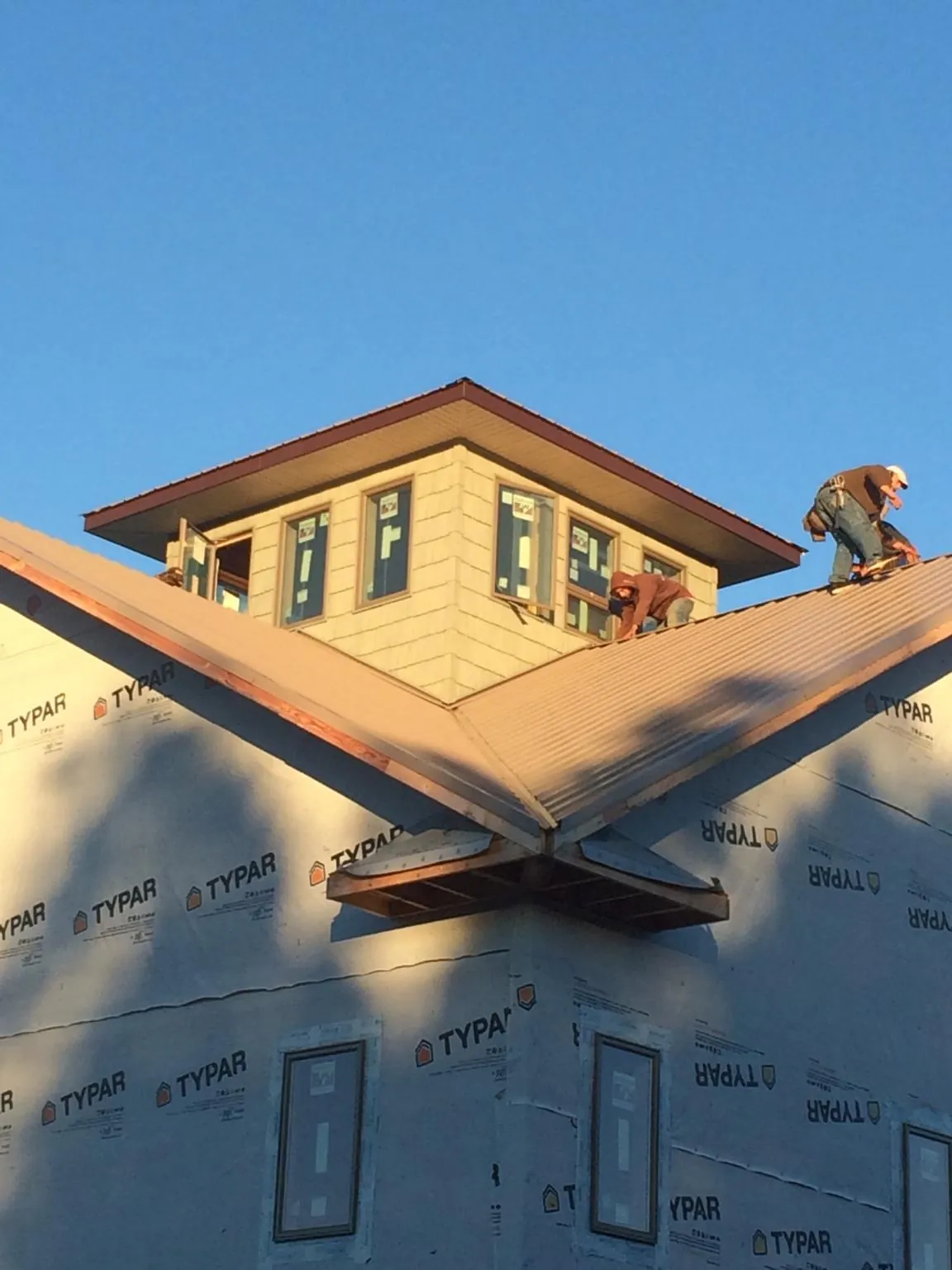 Roofers working around a rooftop cupola on a new metal roof at sunset — Roof Waterproofing in Central Village by Roofing Brothers